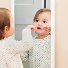 Małe dziecko w lustrze, jakby z bajki o dziecku, odkrywa siebie.
