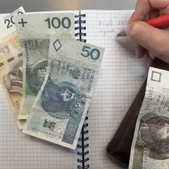 Zapisywanie wydatków na dziecko z orzeczeniem o potrzebie kształcenia specjalnego. Na zeszycie leżą banknoty 200, 100, 50, 10 zł.