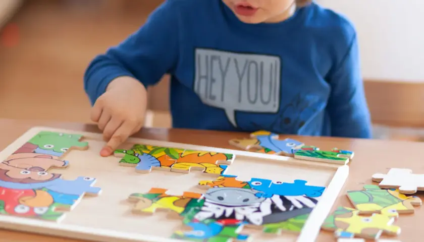 Chłopiec układa kolorowe puzzle z zwierzątkami. To świetne puzzle co rozwijają wyobraźnię i zdolności manualne.