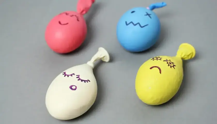 Cztery kolorowe balony z narysowanymi buźkami, gotowe do zabawy. Prosty sposób, jak zrobić gniotka.