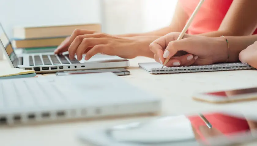 Dwie osoby uczą się, jedna pisze na laptopie, druga notuje. Odkryj skuteczne sposoby na szybką naukę.