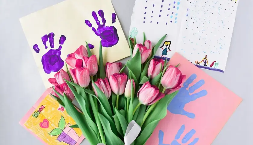 Bukiet różowych tulipanów i laurki z odciskami dłoni – idealny prezent na dzień kobiet w przedszkolu.