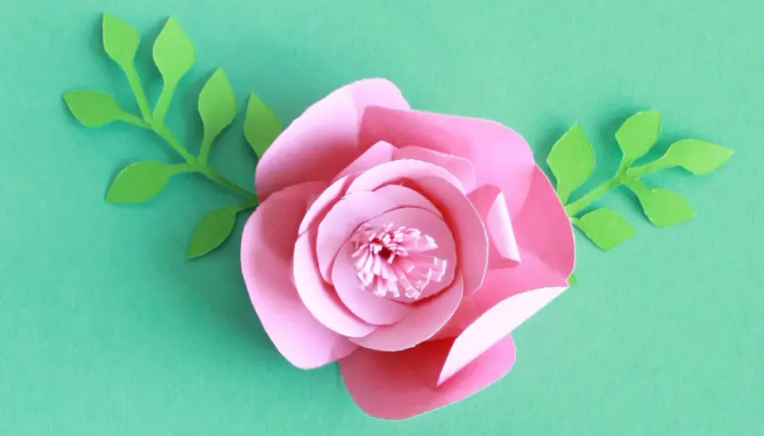 Kwiaty z papieru 3d jak zrobić? Różowa róża z zielonymi listkami, idealna do dekoracji.