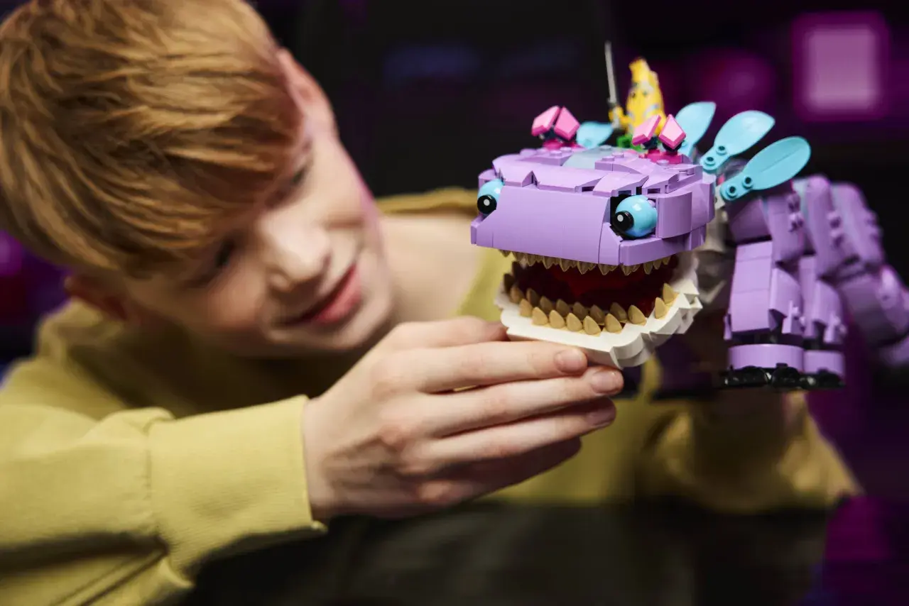 Chłopiec bawi się fioletowym Klombo z Lego Fortnite, z bananem na głowie.