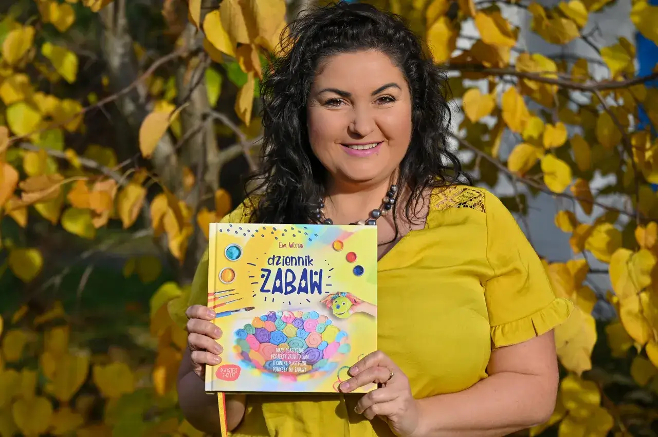 Kobieta w żółtej bluzce trzyma książkę